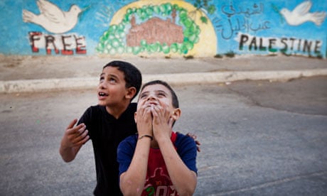 Children play outside a peace mural in the West Bank