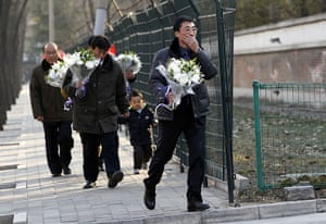 Reaction to Kim Jong il: A man carries flowers towards the North Korean Embassy in Beijing
