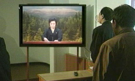 North Korean officials watch a news broadcast announcing death of North Korean leader Kim Jong-il