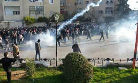 Protesters cover their faces from tear gas being fired in Adlb