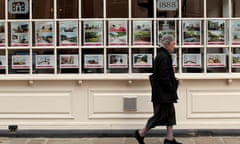 A woman walks past an estate agents in London
