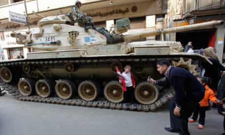A man takes a picture of his daughter next to a tank in Tahrir Square, Cairo 14/2/11