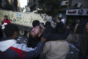 Egypt clashes day 9: An injured anti-government protester is carried past an army vehicle
