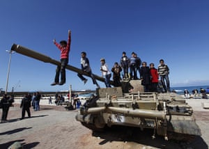 Libya: Boys sit on the barrel of a destroyed army tank in Benghazi