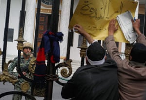 Egypt protests day 16: Protesters attach a sign to the gate of the Parliament building
