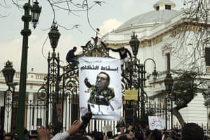 Egypt protests day 16: Protesters hang a cartoon showing President Mubarak outside the parliament