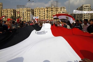 Egypt protests day 16: Anti-government demonstrators hold a huge national flag in Tahrir square
