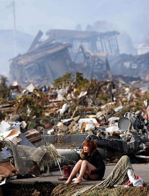 japan disaster aftermath: A woman cries while sitting on a road in Natori