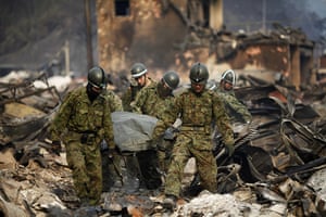 Japan tsunami rescue: Japanese rescue workers carry the body of a tsunami victim
