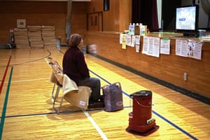 Japan tsunami rescue: A woman watches television coverage in an evacuation centre in Hachinohe