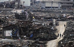 Japan tsunami rescue: People walk on a makeshift dirt road amongst the rubble in Minamisanrikucho