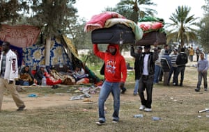 Refugees Flee Libya: Men from Sub-Saharan Africa carry their belongings on their heads