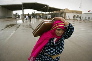 Refugees Flee Libya: A Tunisian woman carries her bags past the Ras Jdir border post