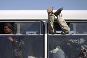 migrant workers flee : A person is helped through a bus window 