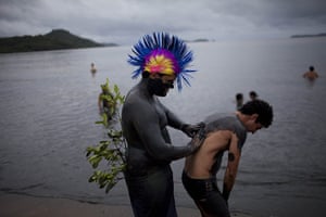 24 hours in pictures: Paraty, Brazil: A man covers a friend with mud during carnival celebrations