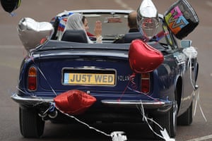 Wedding procession: The couple wave to the crowds in an open-top Aston Martin Volante