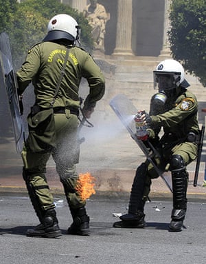 Protests in Athens: A riot policeman extinguishes a fire on a colleague caused by a petrol bomb