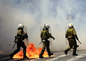 Protests in Athens: Riot policemen run through a cloud of teargas to avoid a petrol bomb
