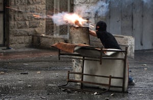 Israel violence: A Palestinian youth throws a firecracker towards Israeli border police