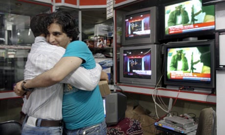 Afghan men hug each other while watching news of the death of Osama bin Laden