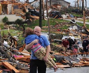 US tornado: A man carries a young girl who was rescued after a tornado