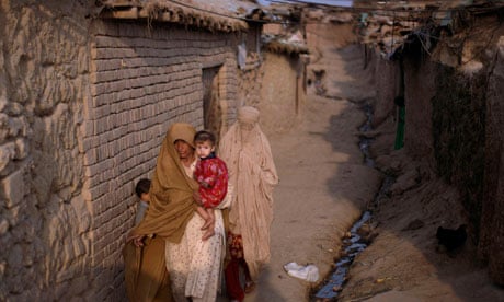 Women with a baby walk in a slum alley on the outskirts of Islamabad, Pakistan