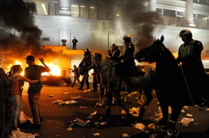 Vancouver riots: Police on horseback ride through the street past a fire