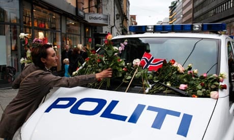 A woman places flowers on a police vehicle after Oslo memorial march