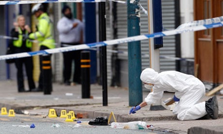 A forensics officer inspects the scene where three men were killed in Winson Green, Birmingham