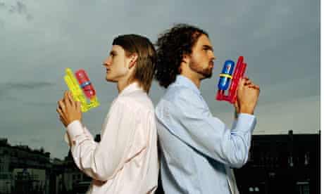 Two men standing back to back holding water pistols