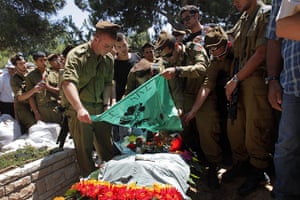 Israeli air strikes: Israeli soldiers place their unit's flag over the grave of their comrade