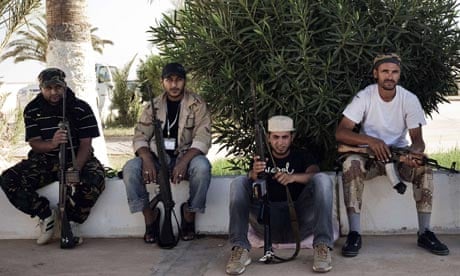Libyan rebel fighters rest outside a mosque as they prepare to advance on Sirte