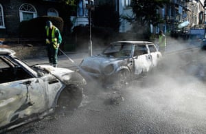 London riots day 4: A cleaner hoses down the street around burned out cars set alight, Hackney 