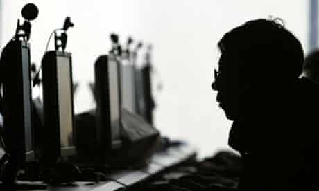 A computer user is silhouetted with a row of computer monitors at an internet cafe in China