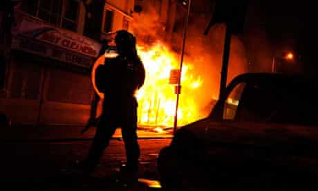 A riot policeman advances past a burning building in Croydon
