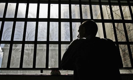 An inmate looks out through the window of a prison