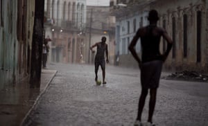 24 Hours: Two young men kick a soccer ball around in the rain in Havana