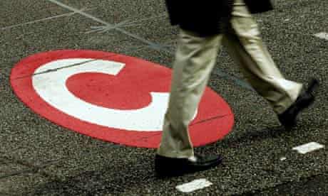 A man walks past a congestion charge sign on the road.
