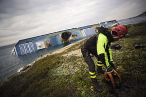 costa concordia: A rescuer prepares on the shore in front of the stricken ship