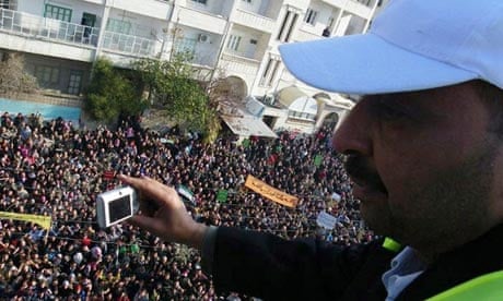 An Arab League observer takes photographs of anti-government protesters in Adlb