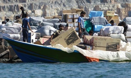A smuggler loads a TV on to his speedboat in Khasab, Oman, to cross the Strait of Hormuz to Iran