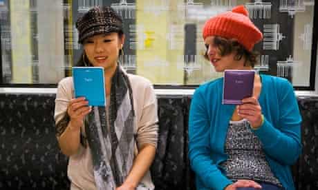 Two models on a subway using e-readers