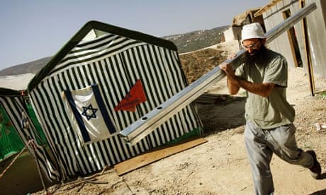 A Jewish settler carries bars for a house he is building in the West Bank