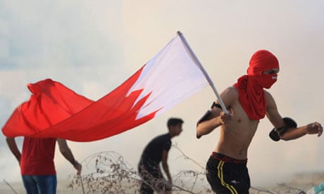 A masked pro-reform protester holds the Bahraini flag