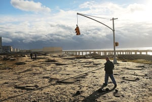 Coastal aftermath update: A man walks by the remains of part of the historic Rockaway boardwalk