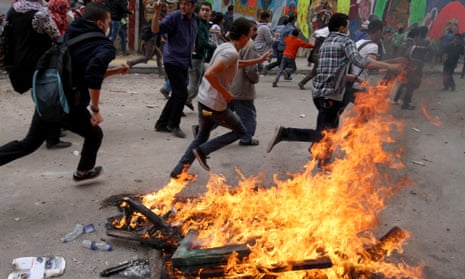 Egyptian protesters run past a bonfire during clashes with security forces in Cairo on Wednesday