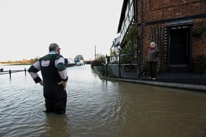 Autumn weather: A man speaks with a passing woman as he stands in floodwaters in Tewkesbury