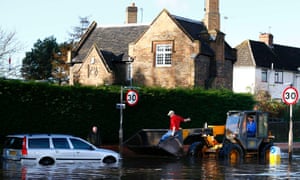 A man is driven in a digger bucket to rescue a car from flood water in Hathern.