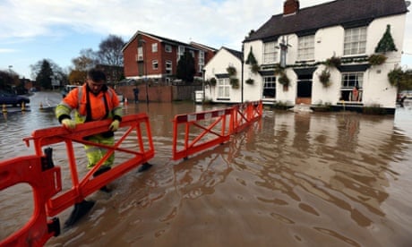 A highways agency worker barriers off the road outside the White Bear Pub in Tewkesbury to stop motorists driving through flood water and flooding the pub further.