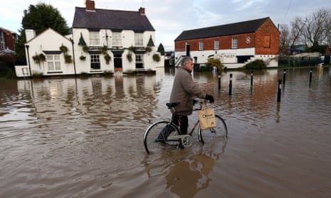 A pedestrian pushes his bike through flood water in Tewkesbury on 26 November 2012.